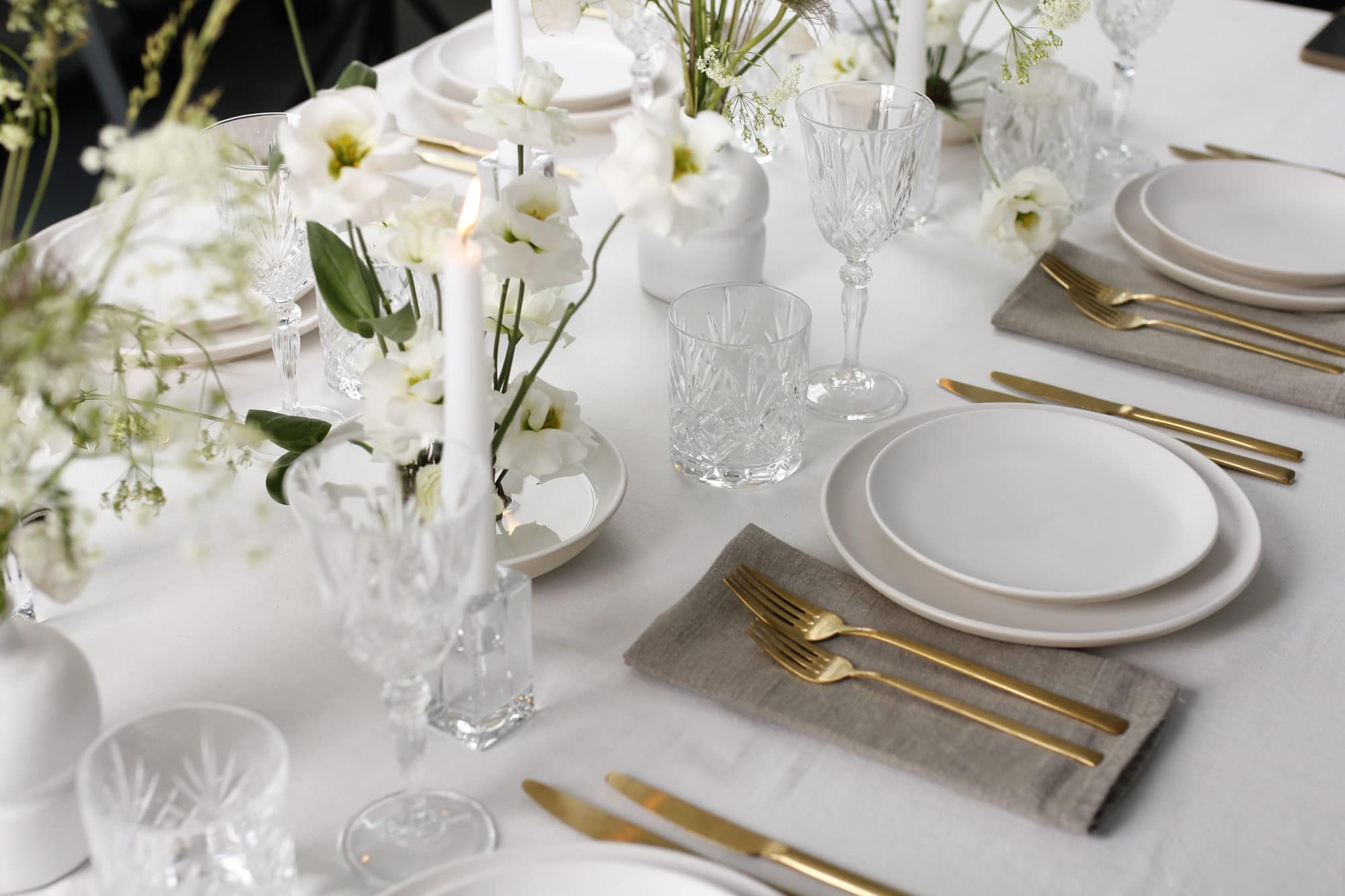 Eleganter gedeckter Tisch mit weißen Blumen und Kerzen.
